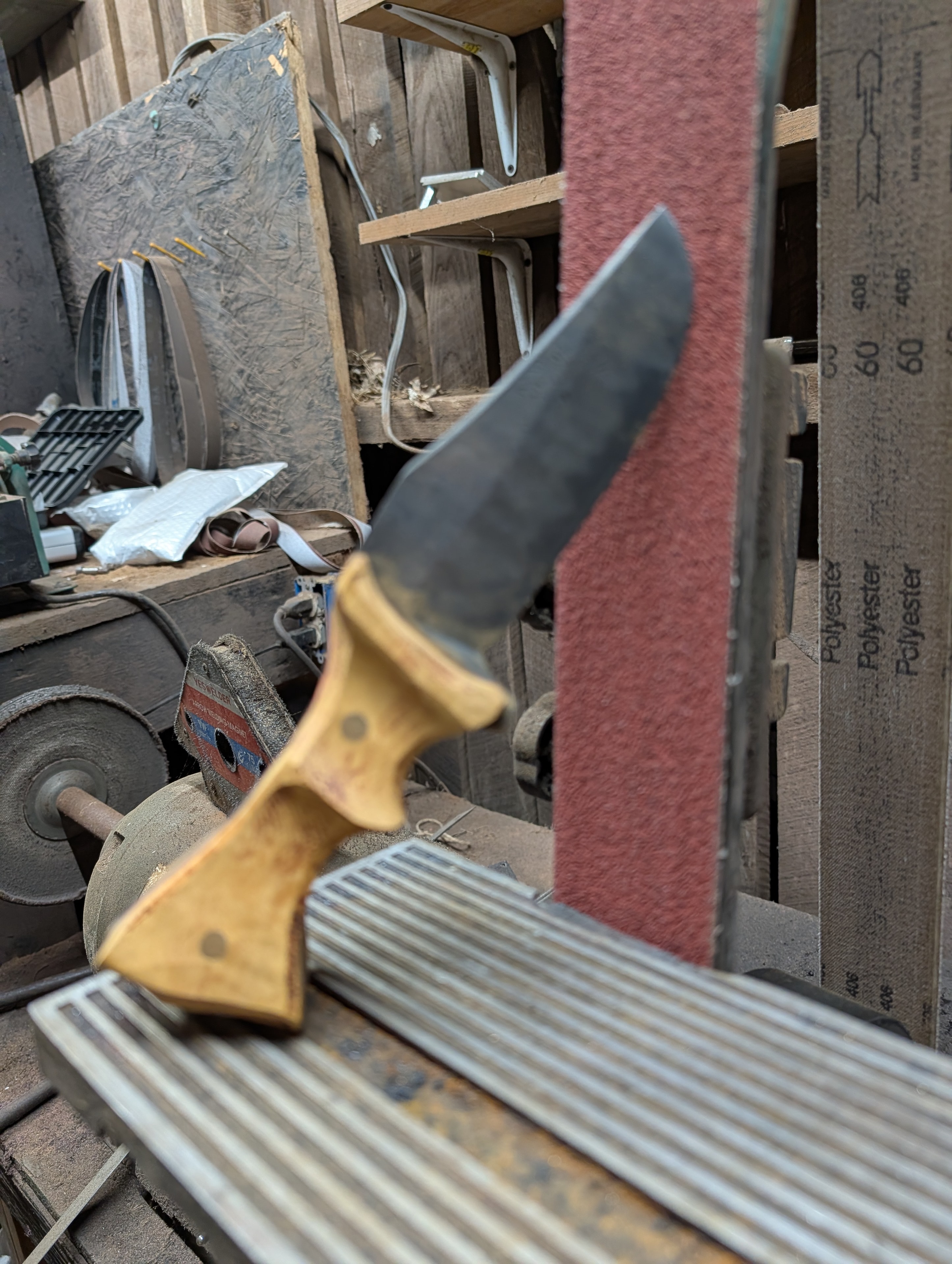 Knife blank on the belt grinder in the workshop