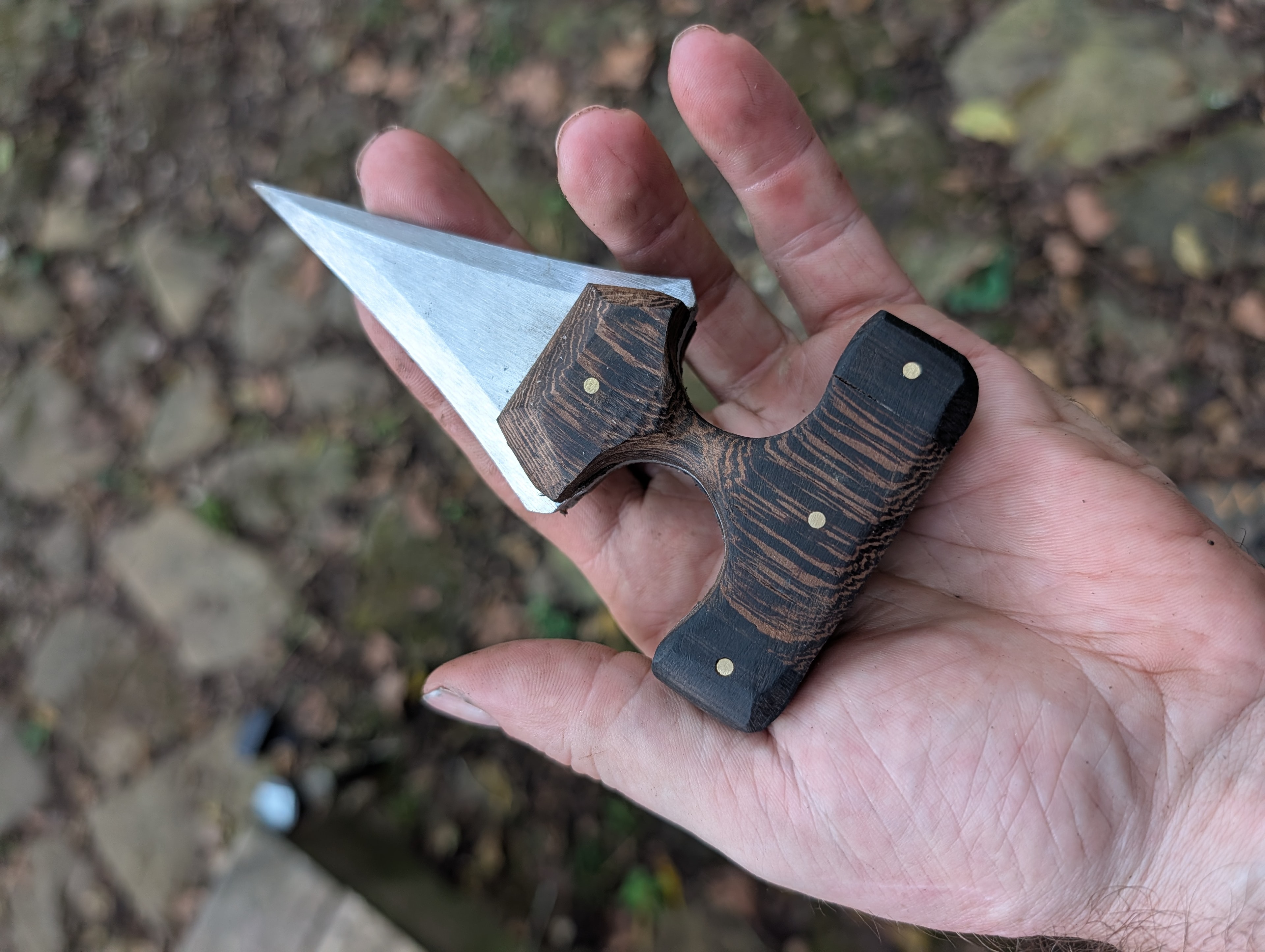 Compact push dagger with dark wood handle held in hand