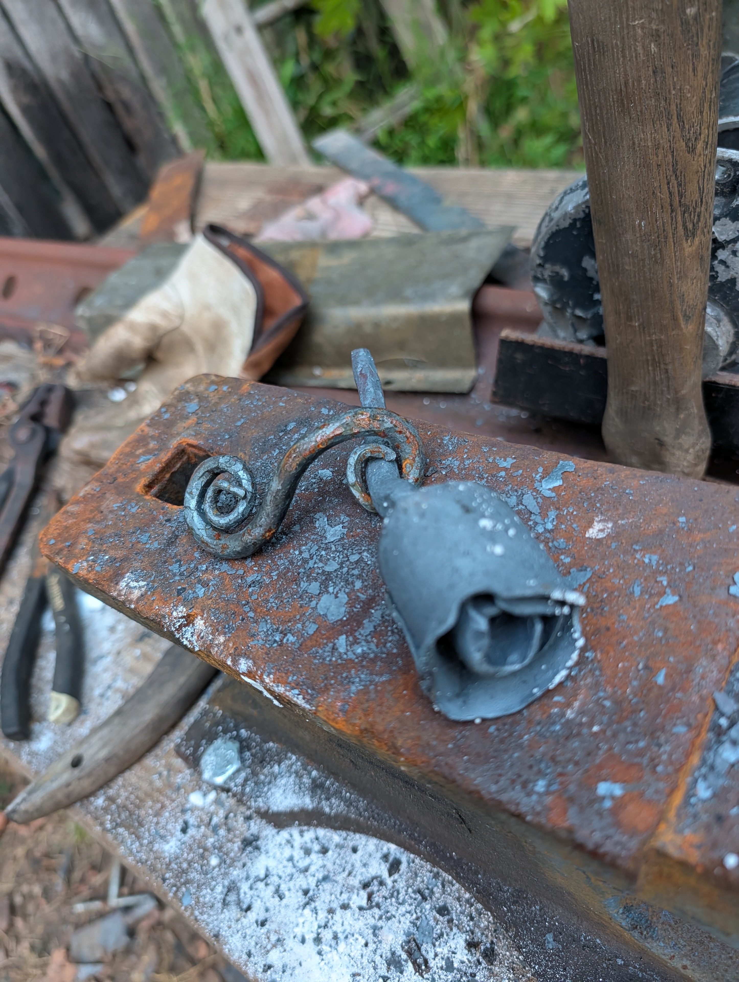Forged metal rose and scroll work cooling on the anvil